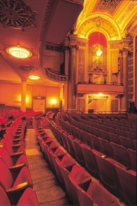 Rows of red theatre chairs curve into the gorgeous, golden walls and ceilings of The Strand Theatre.