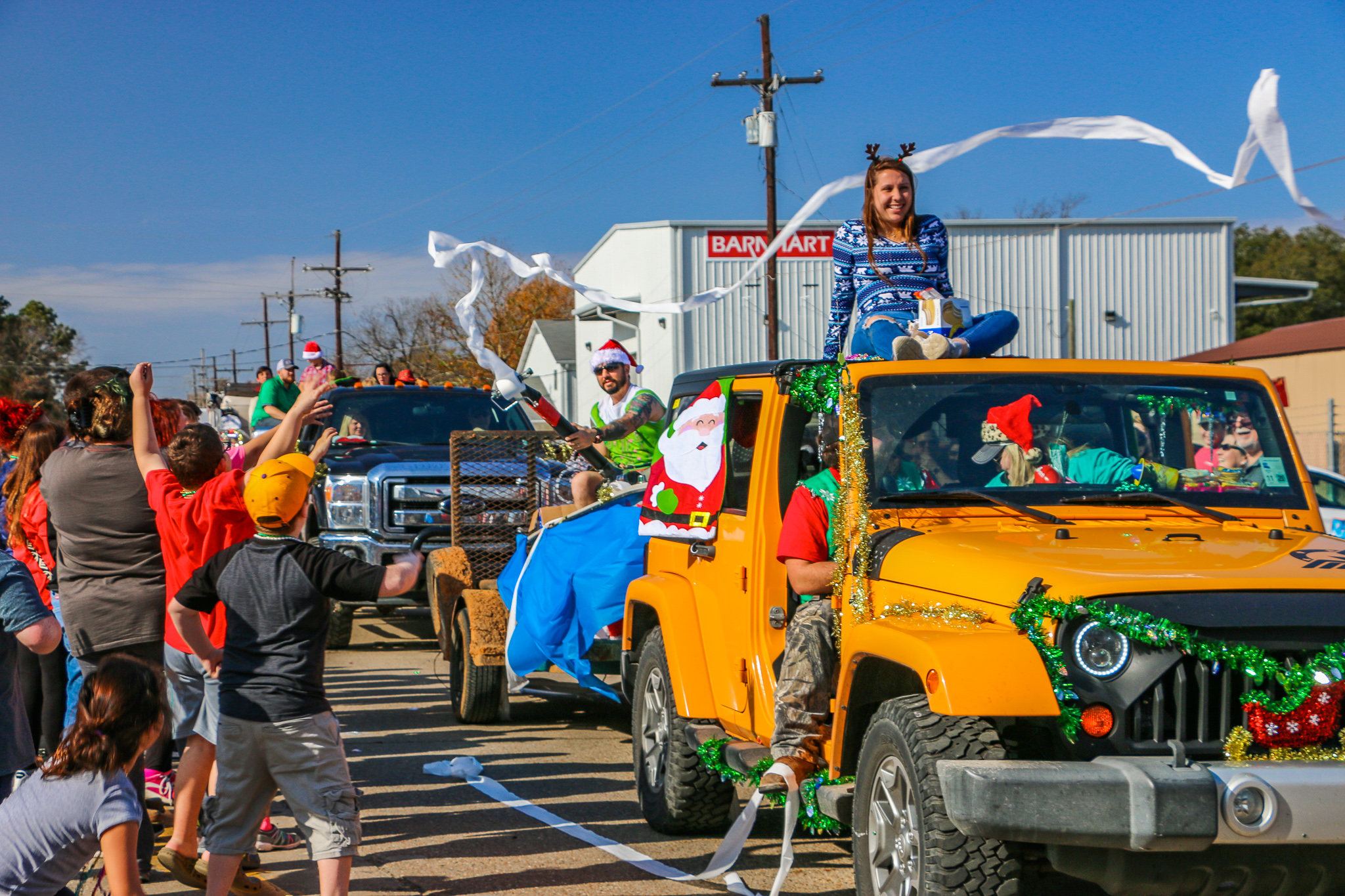 yellow jeep in a parade with toilet paper being thrown from jeep